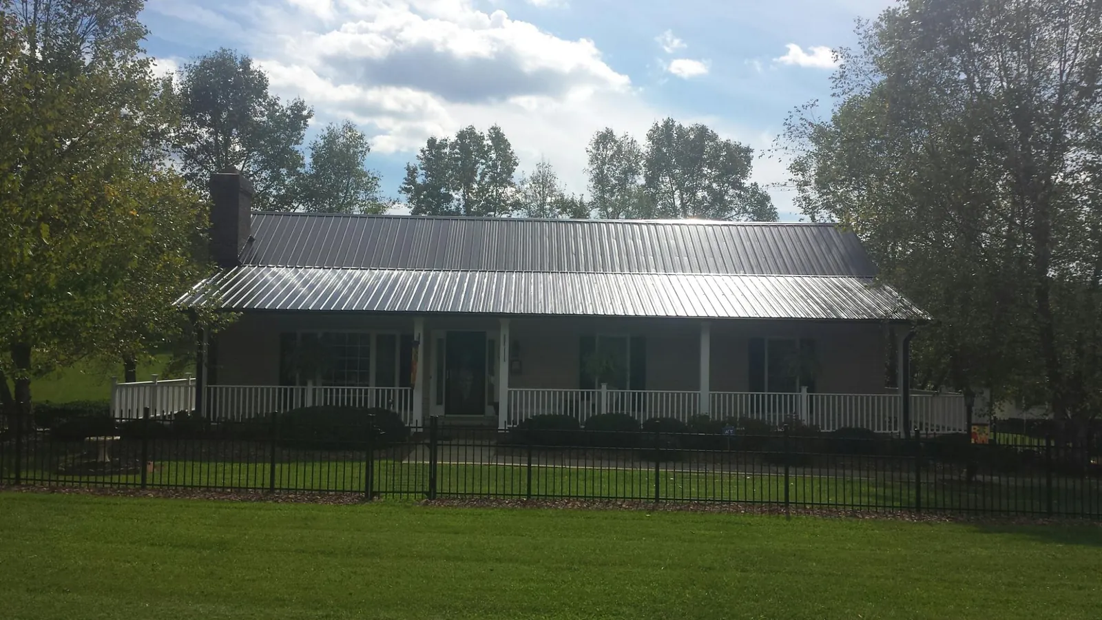 Gray metal roof on a brick ranch with a full width front porch — Gutter Guard Installation work by our crew in Hinton